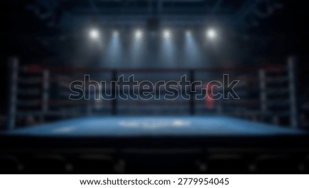 An empty boxing ring is illuminated by bright overhead lights, creating a dramatic atmosphere. The blue canvas floor and the ropes are clearly visible, with the focus on the center of the ring, ready for a match.