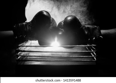 Empty boxing ring with red ropes for match in the stadium arena. Boxing gloves ready to fight. Empty space for text. Foggy background with light. Selective focus