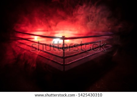 Empty boxing ring with red ropes for match in the stadium arena. Creative artwork decoration. Foggy background with light. Selective focus