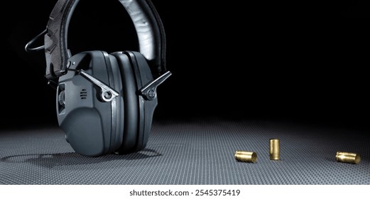 empty brass next to electronic hearing protection for shooting on a dark background with copy space