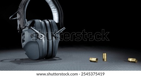 empty brass next to electronic hearing protection for shooting on a dark background with copy space