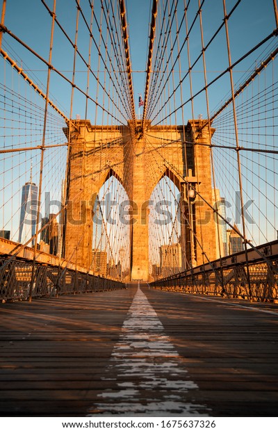 An empty Brooklyn\
Bridge during sunrise.