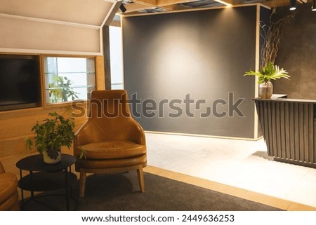 Empty brown armchair sitting next to small table with plants. Warm lighting complements wooden accents and cozy interior design, unaltered