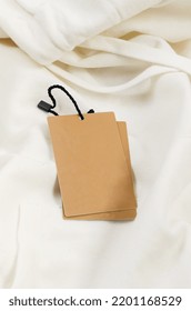 Empty Brown Cardboard Tag With String On White Jersey Hoodie. Vintage Paper Textured Mockup Cardboard Label. Price, Sale Tag, Address Label. Shopping Concept. 