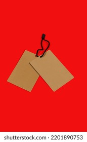 Empty Brown Cardboard Tag With String On Red Background. Vintage Paper Textured Mockup Cardboard Label. Price Tag, Gift Tag, Sale Tag, Address Label. Shopping Concept. 