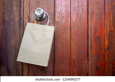 Empty Brown Paper Shopping Bag Hanging On Old Wooedn Door Background