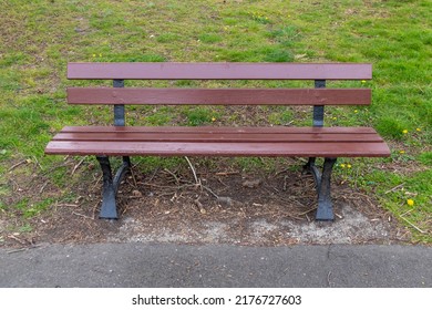 Empty Brown Wooden Park Bench In A Suburban Park