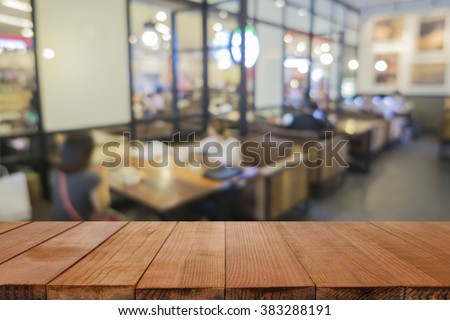 Empty brown wooden table and Coffee shop interior with some people meeting blur background with bokeh image,can be used for montage or display your products