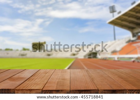 Empty brown wooden table top on blurred background of Red running tracks in sport stadium - can be used for display or montage your products