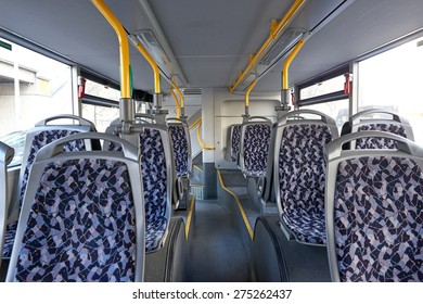 Empty Bus Seats With A Blue Pattern And Yellow Handlebars Above Them