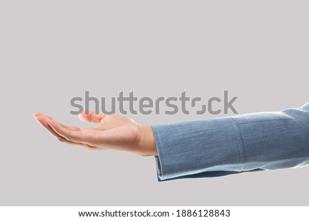 Empty businesswoman hand holding isolated on gray background. Blank woman hand and blue suit sleeve.