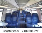 Empty cabin of a modern passenger train. Empty blue seats inside train cabin, corridor view, no people. Modern european economy class fast train interior. Inside of high speed train compartment