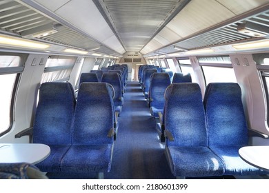 Empty Cabin Of A Modern Passenger Train. Empty Blue Seats Inside Train Cabin, Corridor View, No People. Modern European Economy Class Fast Train Interior. Inside Of High Speed Train Compartment