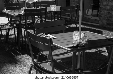 Empty Cafe Outdoor Terrace Setting For Lunch In Sunny Day. Nobody. Abandoned Lifestyle Background. Impossible Dinner Party, Socializing Limits, Economic Crisis Concepts. Black White Historic Photo