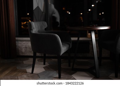 Empty cafe or restaurant at night or in the evening. An empty gray suede cross stands at a round table.