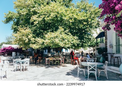 Empty cafe tables on streets of village of Tinos island with Cycladic houses on background, Cyclades, Greece - Shutterstock ID 2239974917