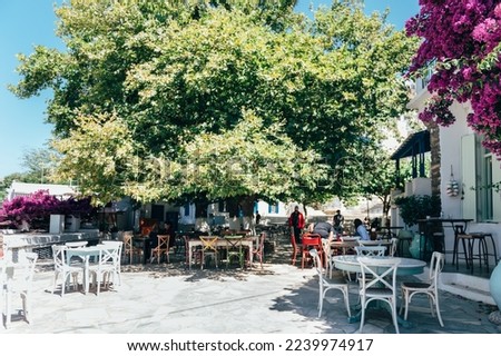 Empty cafe tables on streets of village of Tinos island with Cycladic houses on background, Cyclades, Greece Imagine de stoc © 