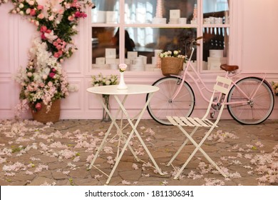 Empty cafe terrace with white table and chair. Pink exterior of the cafe restaurant. interior Street cafe. Cozy street with flowers and French-style cafe table. Decor facade of coffeehouse with bike.  - Shutterstock ID 1811306341