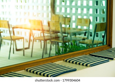 An empty cafe without customers ,blank chairs and tables with the silhuette light on the big window glass. 
