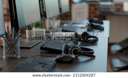 Empty call center office with computers and audio headsets used to have conversation with people on customer service helpline. Nobody at telemarketing workstation with technology.