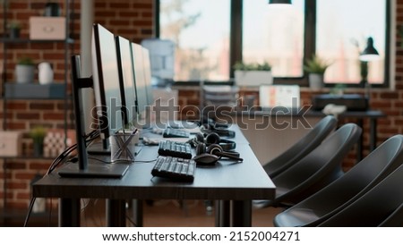 Empty call center workstation with headsets and computers, used by people working at customer care service. Nobody in office with headphones, microphones and monitors for helpline support.