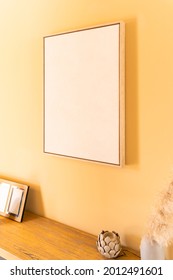 Empty canvas, poster, wooden art frame, mock up, on a yellow wall, living room, home paintings decoration template, low angle view
