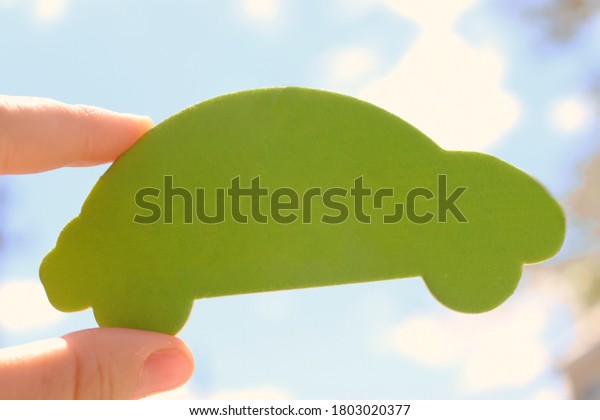 Empty car shape for an advertising. Green car\
shape holded by woman or girl hand against the sky. light blue\
background. car air\
freshner.