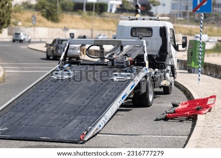 An empty car tow truck stands at the curb