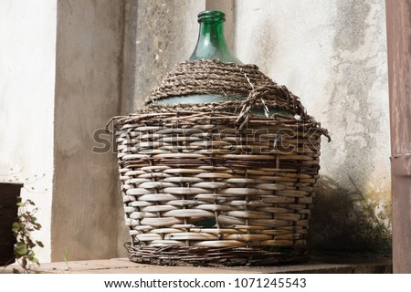 Empty carboy in rustic house, leaning against the wall