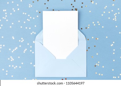 Empty Card In Blue Envelope On Blue Background Decorated With Confetti. Holiday And Invitation Mockup.