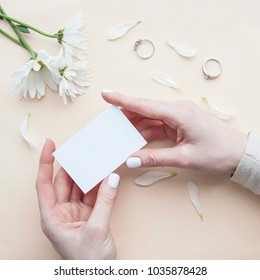 Empty card with rings and flowers.  Top view composition with girl's hand holding card. Flat lay business card. Mockup template. View from above.