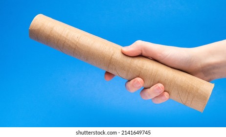 Empty Cardboard Tube In Hand Angled On A Blue Background