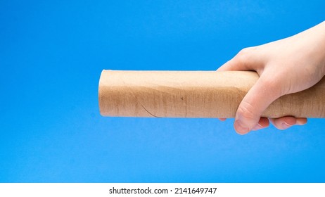 Empty Cardboard Tube In Hand On A Blue Background