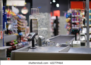 Empty cash desk with computer screen and card payment terminal on blurry background