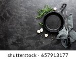 Empty cast iron frying pan on dark grey culinary background, view from above