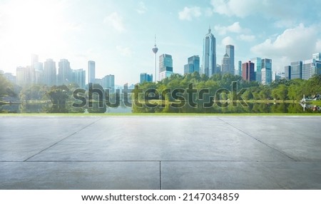 Empty cement floor with lake garden and modern city skyline in background.