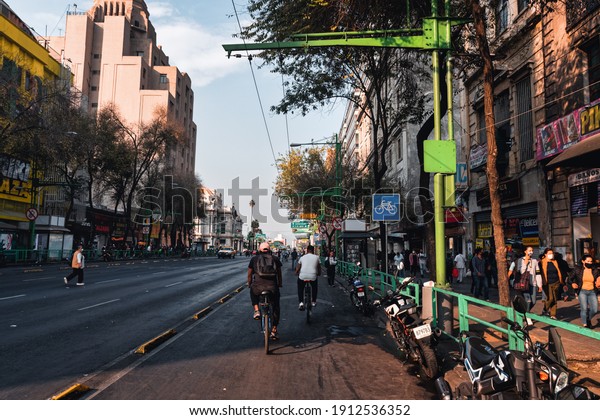 Empty central street of Mexico city Eje Central\
street or Avenida Lazaro Cardenas with no cars because of\
coronavirus pandemic and cyclists and people walking along road,\
Mexico, in January 25,\
2021