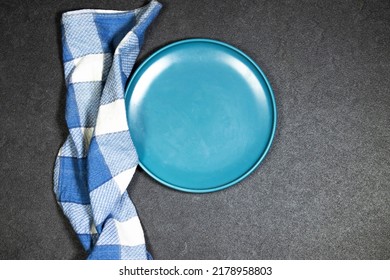 Empty Ceramic Blue Plate On Grunge Gray Background With Plaid Napkin