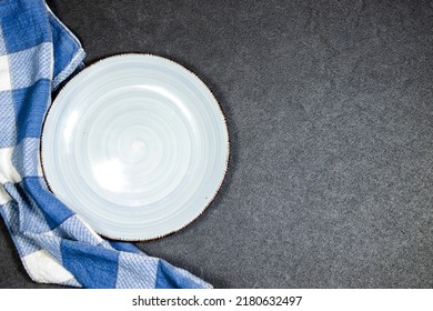 Empty Ceramic Blue Plate On Grunge Gray Background With Plaid Napkin