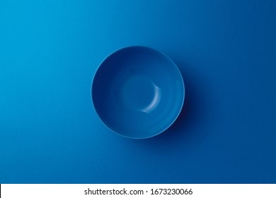 Leere, keramik-blaue runde Platte auf klassisch blauem Hintergrund. Draufsicht. Flat lay. Kopiert Platz. Minimales kreatives Konzept. Trendfarben 