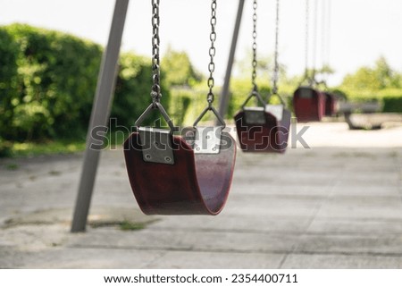 Empty chain swing in the park on a blurred background, close up swing seat.