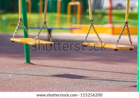 Empty chain swings on summer kids playground