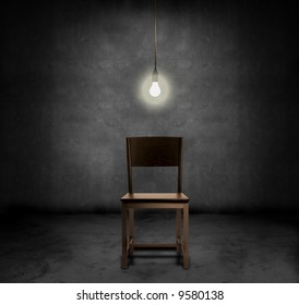 An empty chair and hanging light bulb in a dark room