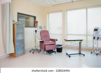 Empty Chair With IV Drip Stand And Table In Chemo Room