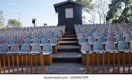 Empty chairs representing an audience seating area set against a backdrop of a clear blue sky.