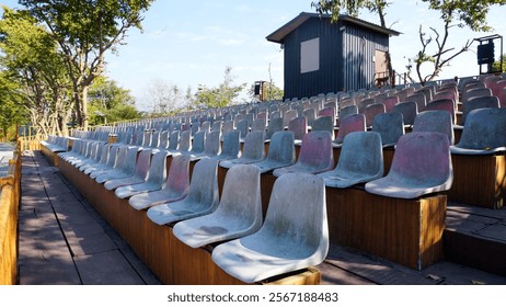 Empty chairs representing an audience seating area set against a backdrop of a clear blue sky.