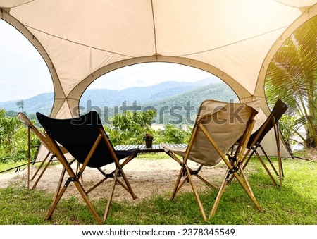 Empty chairs and tables placed under dome tents to admire the mountain view.