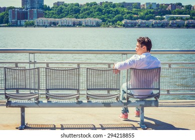 Empty Chairs for You. lonely man seeking friendship. Wearing white shirt, jeans, sneakers, a young lonely guy sitting by Hudson River in New York, facing New Jersey, waiting for you. Copy Space. 