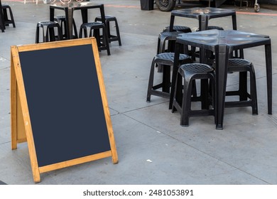 Empty chalkboard next to tables and chairs and a food truck in a square in Brazil - Powered by Shutterstock