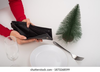 Empty Christmas Wallet. A Woman Is Holding A Purse With No Money On An Empty Holiday Table. The Financial Crisis During The Holidays.